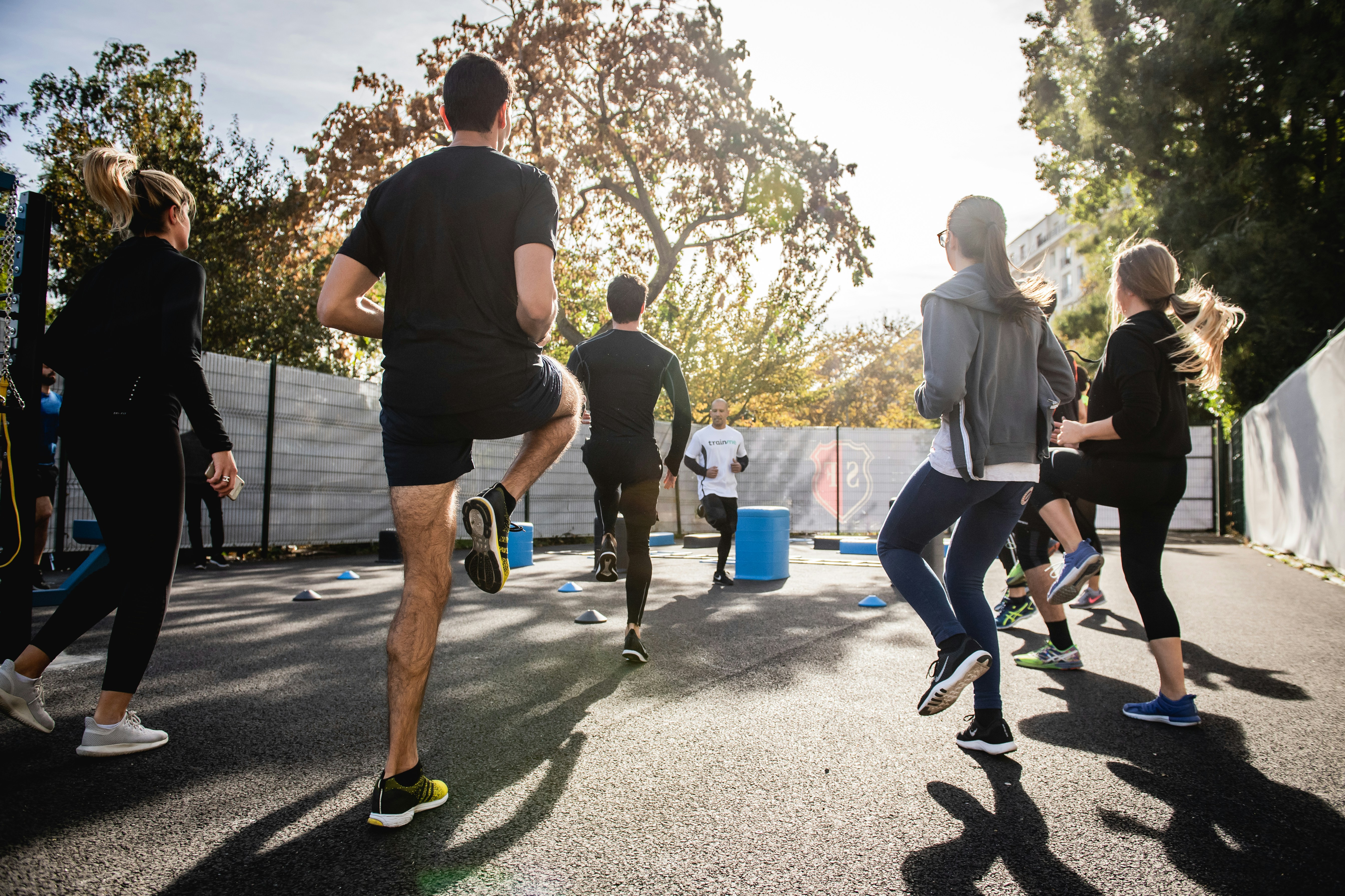 Eine Gruppe von Menschen steht draußen im Kreis und macht Fitnessübungen.