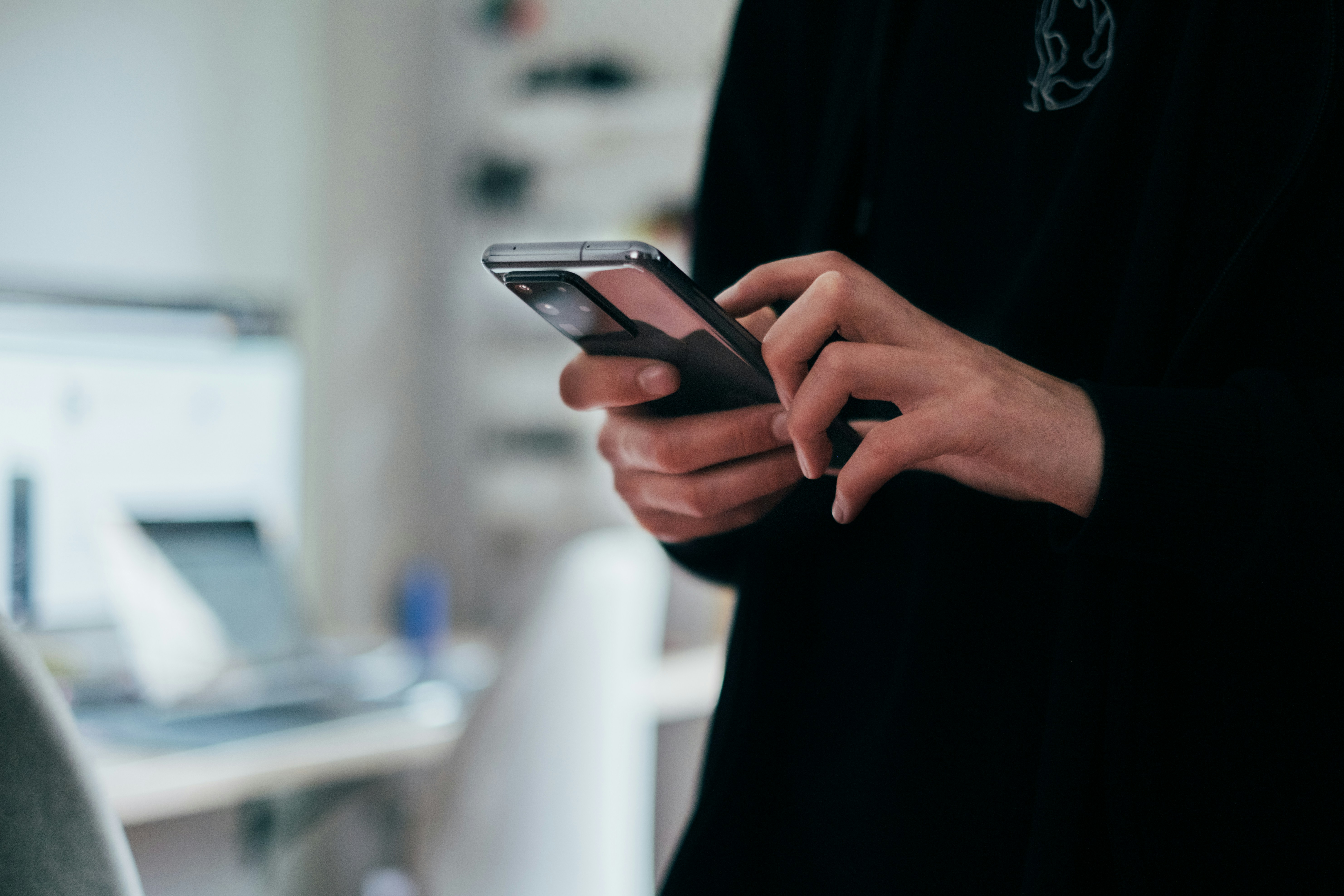 Nahaufnahme der Hände einer Frau, die ein Smartphone in der Hand hat und darauf tippt.