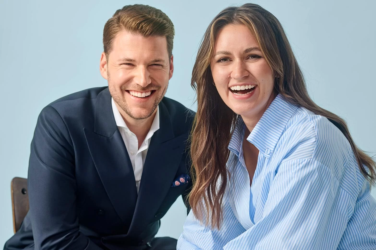 Mann und Frau in Business Outfit lachend mit Blick in die Kamera