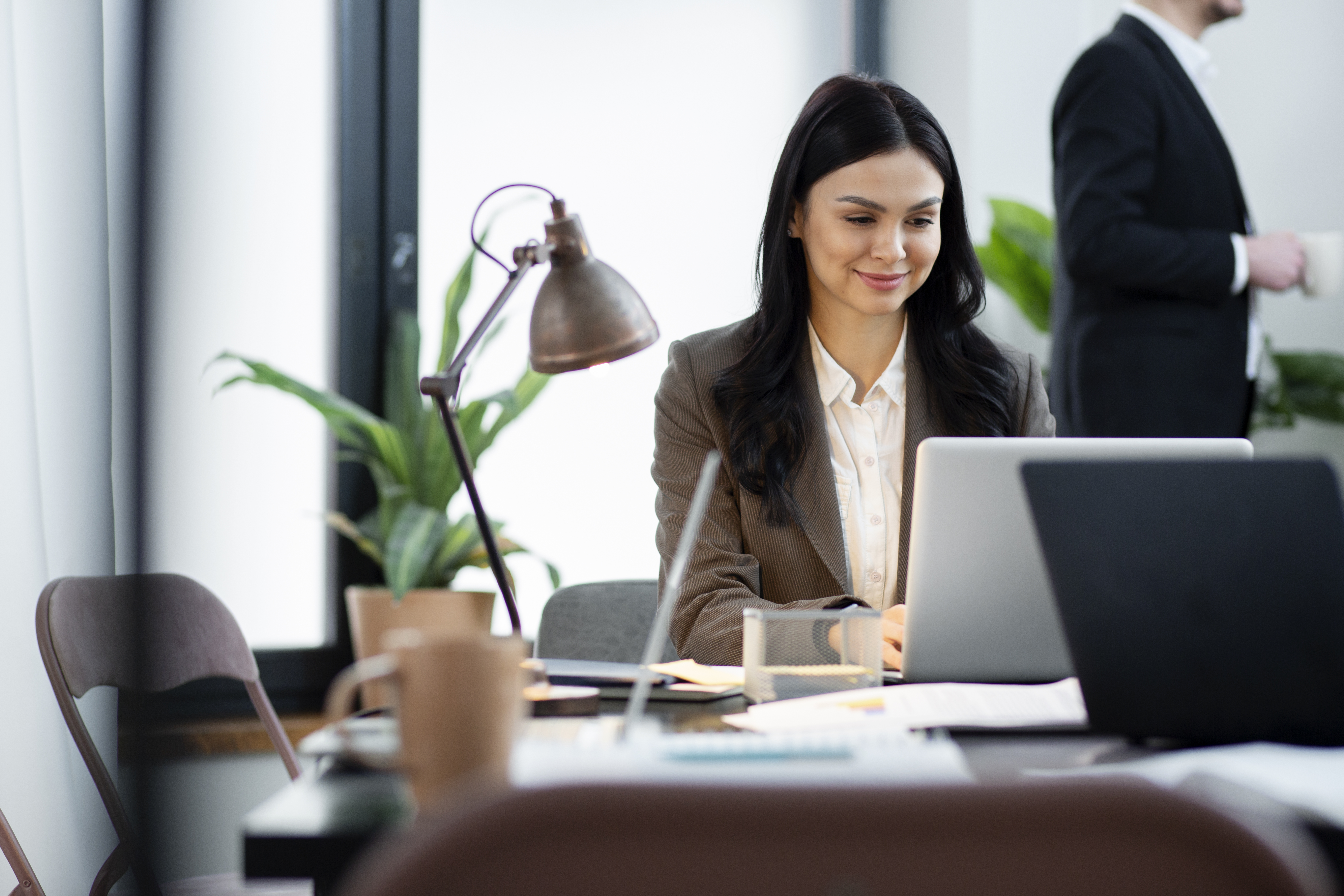 Eine Frau sitzt am Schreibtisch und arbeitet am Laptop