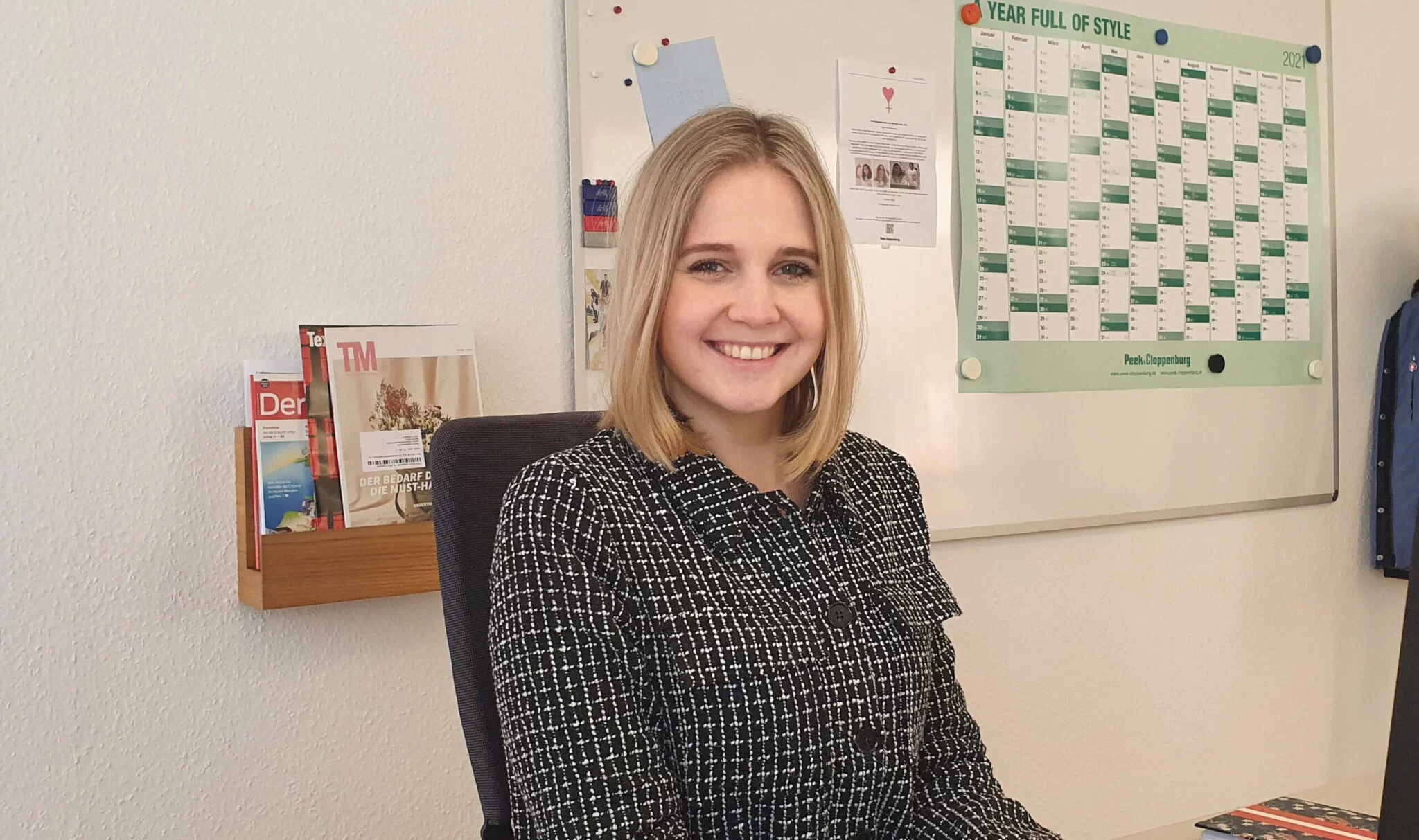 Saskia sitzt im Büro und lächelt in die Kamera. 